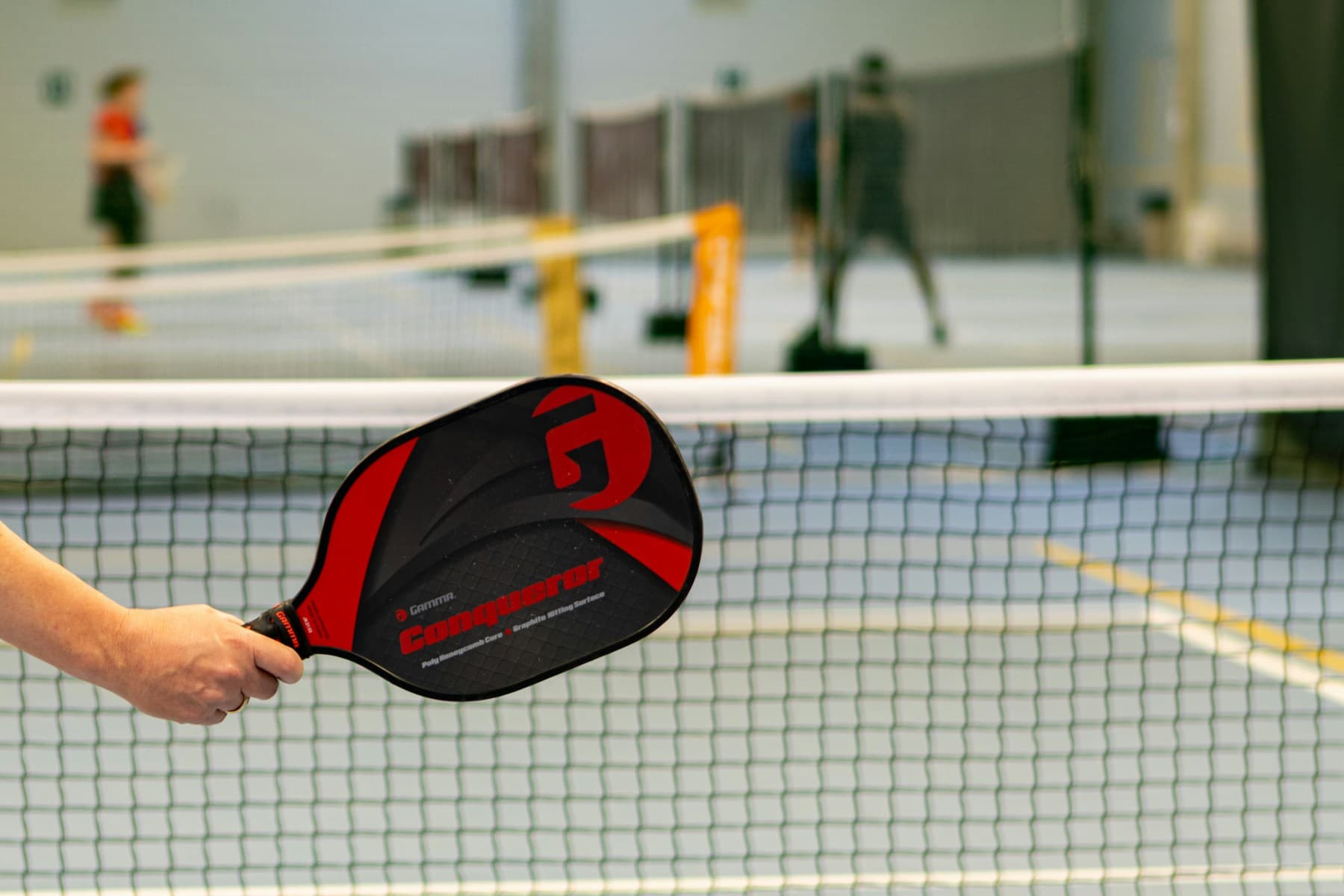 Pickleball player at an indoor court net