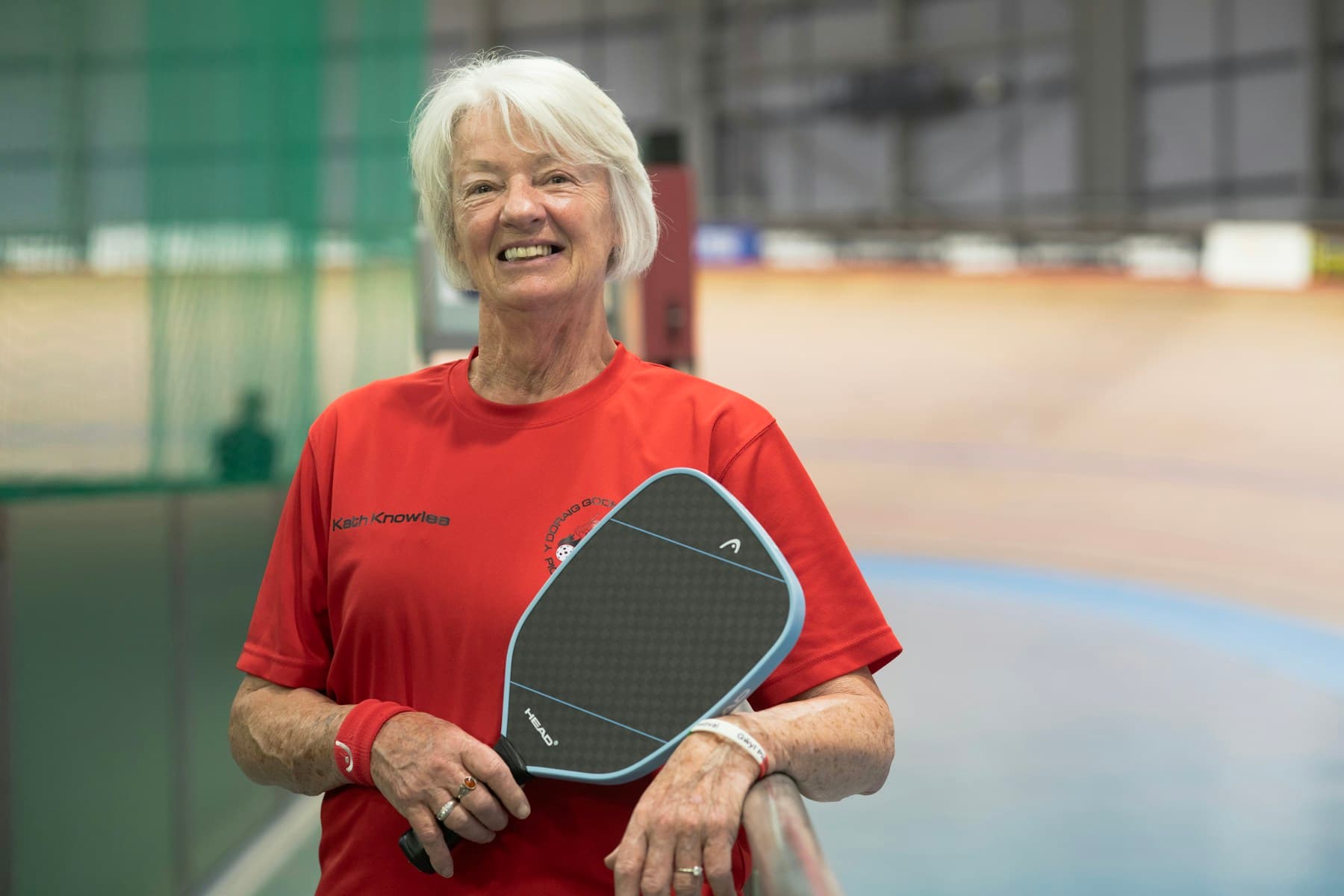 A smiling pickleball player holding her paddle